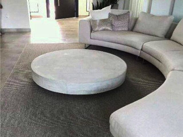 mesa de sala redonde y moderna en cemento y frenta al sofa