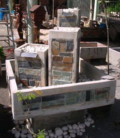 fuente de jardín con piedras y varias torres y chorros