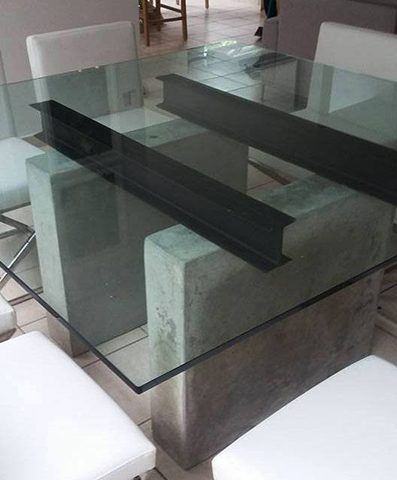 bases de cemento, bigas de acero y tope de cristal para crear una mesa moderna
