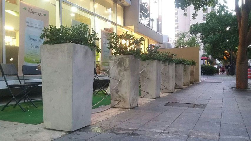 tiestos de cemento rodeando unas plaza de mesas en restaurante